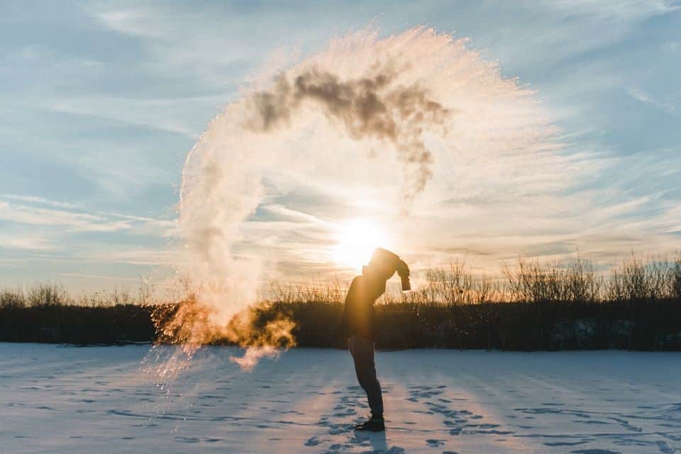 Persoon in een balanshouding in een besneeuwd landschap bij zonsopkomst